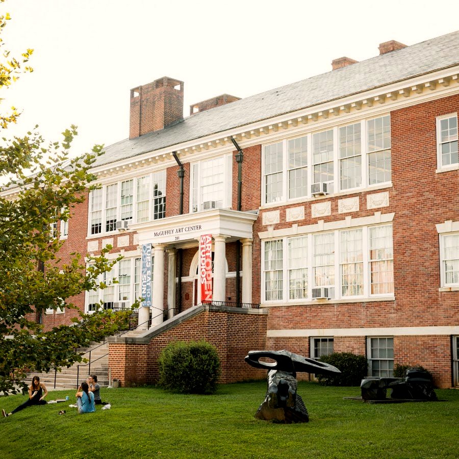 The McGuffey Art Center — a two-story brick 1915 schoolhouse with a columned entrance, sculptures and people on the front lawn.
